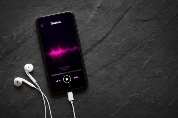 Music player on mobile phone with earphones on black background